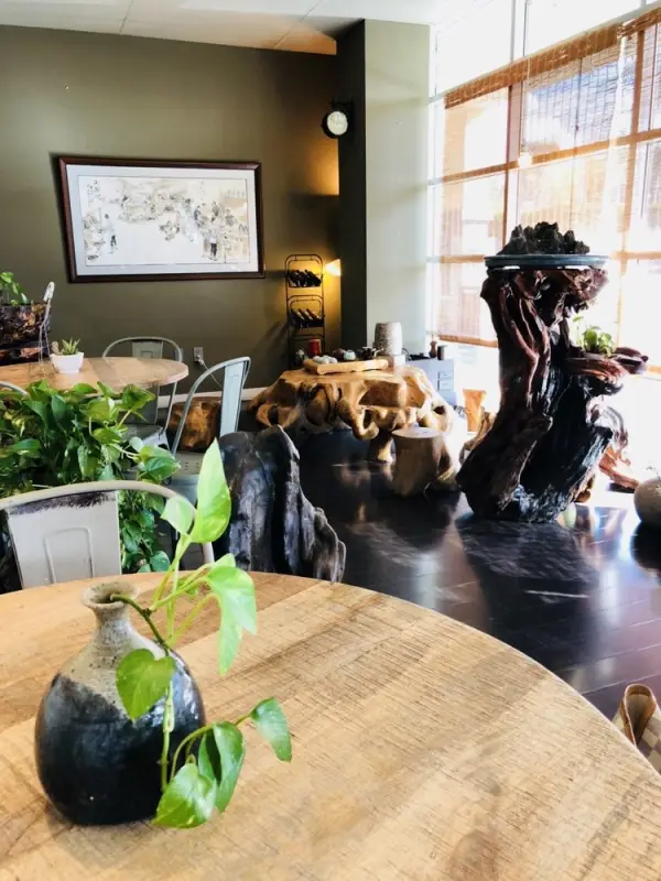 Inside Health Station: wooden tables, plants, a framed painting and carved wood decor